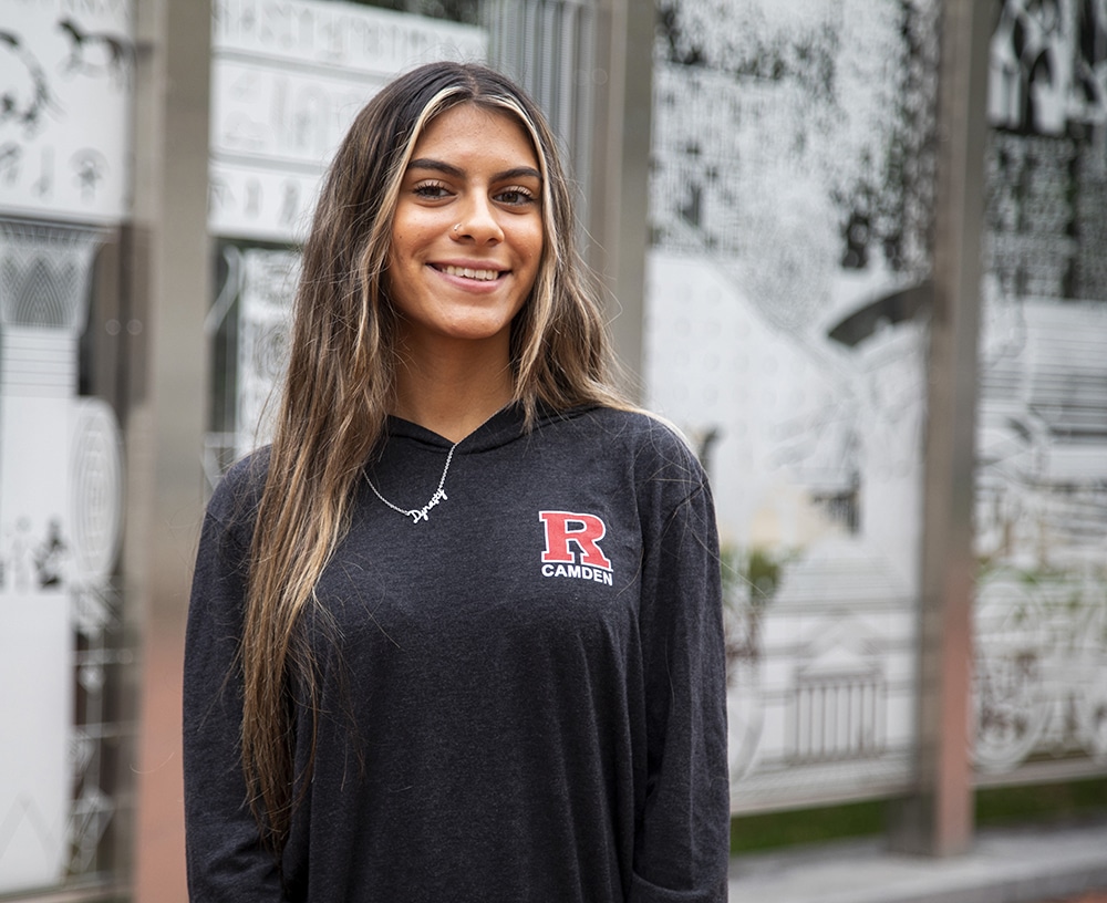 A Rutgers student smiling inside a campus building